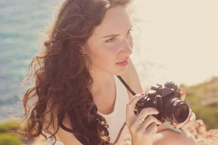 Portrait of tourist smiling girl making photos of the nature views by old camera on the peak of...