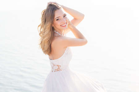 Beautiful smiling young bride girl is sitting over the sea viewの写真素材
