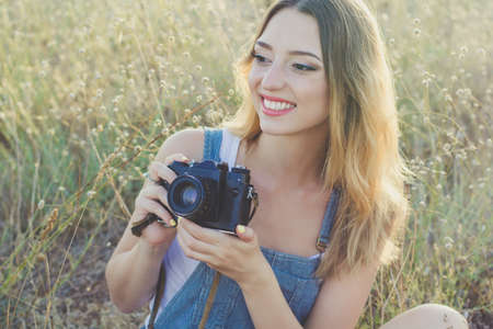 Portrait of tourist smiling girl making photos of the nature by old camera summer timeの写真素材