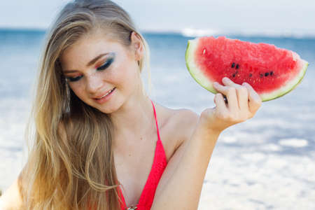 Beauty teenager girl eating watermelon near seaの写真素材