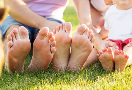 Closeup picture of family feets lying in line at green grassの写真素材