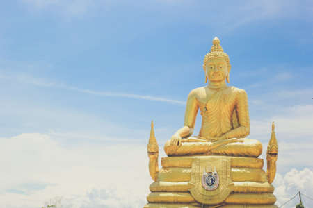 Golden sitting Buddha statue over blue sky background in temple of Thailand, Phuketの写真素材
