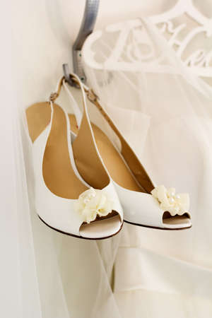 Bride white wedding shoes is hanging on hangerの写真素材