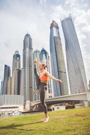 Young girl doing stretching against skyscrapersの写真素材