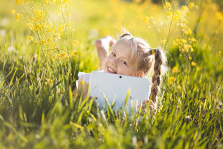 Little blonde girl with digital tablet on the natureの写真素材