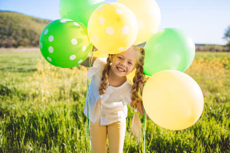 Little happy girl with green and yellow balloonsの写真素材