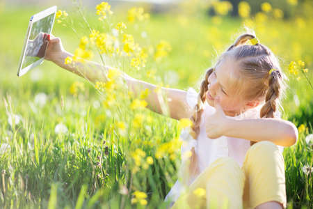 Little blonde girl taking selfie in yellow fieldの写真素材