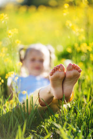 Feet of little girl in yellow field with flowersの写真素材