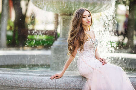 Woman is wearing luxury dress near antique fountainの写真素材