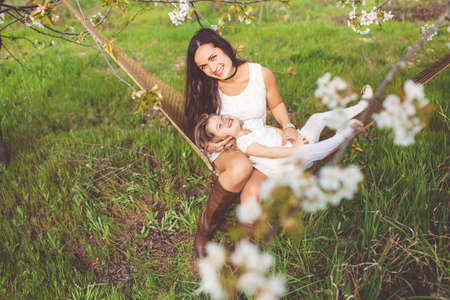Happy girl with mother are resting in hammock outdoorsの写真素材