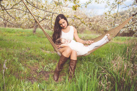 Mother and daughter are resting in hammock outdoorsの写真素材