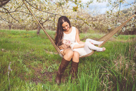 Happy mother and daughter are resting in hammock outdoorsの写真素材