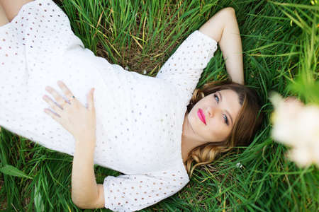 Smiling pregnant woman lying in grassの写真素材