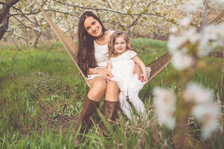 Happy mother and child girl are resting in hammock outdoorsの写真素材