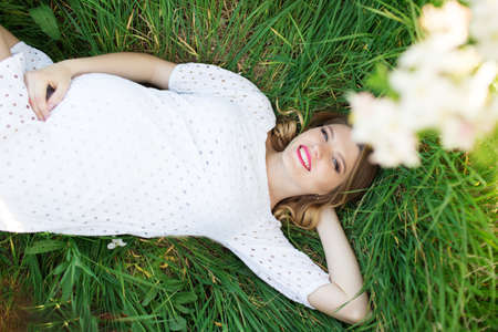 Happy pregnant woman lying in grassの写真素材