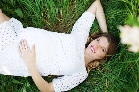 Happy pregnant woman lying in grassの写真素材