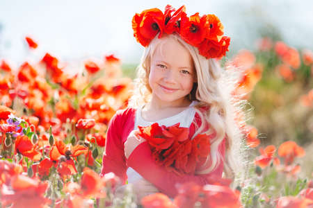 Cute blonde child girl in poppy fieldの写真素材