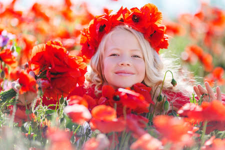 Cute blonde child girl in poppy fieldの写真素材