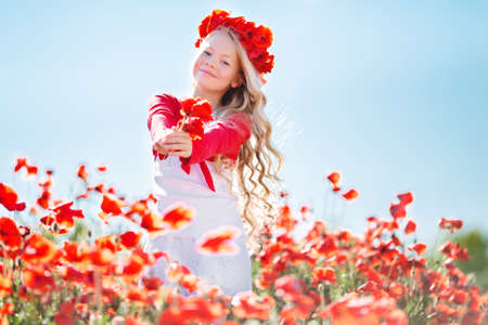 Cute blonde child girl in poppy fieldの写真素材
