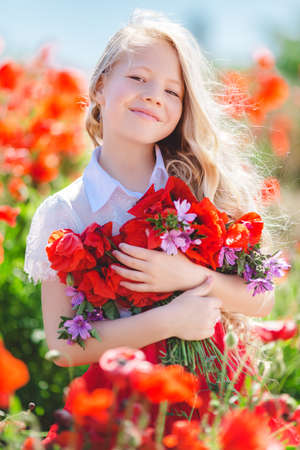 Pretty child girl with bouquet of red poppiesの写真素材