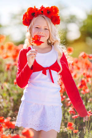 Pretty blonde child girl in spring field with poppiesの写真素材
