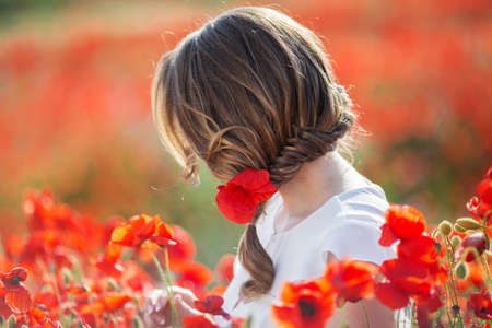 Beautiful woman in field of poppy flowers, spring time