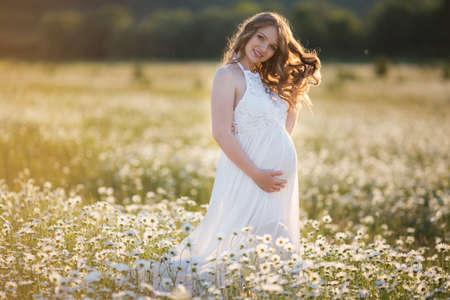 Beautiful pregnant woman on the camomile fieldの写真素材