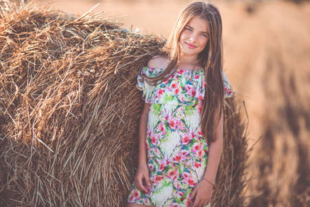 Pretty girl near stack of hay in the fieldの写真素材