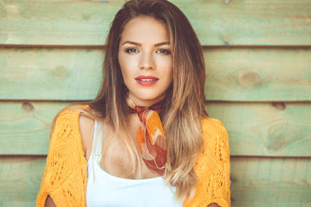 Fashion woman is wearing yellow sweater over wooden background