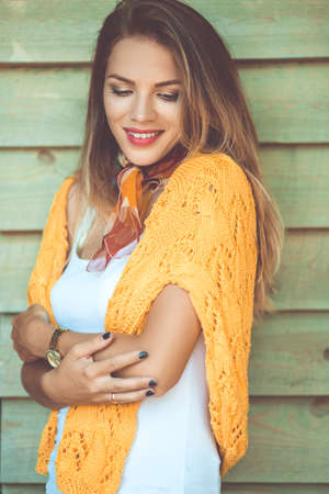 Fashion woman is wearing yellow sweater over wooden backgroundの写真素材