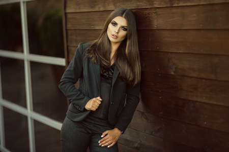 Portrait of fashion serious business girl is wearing black official clothes near big glass windows...