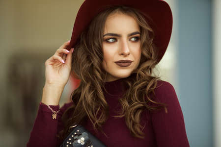 Portrait of beautiful elegant woman is wearing fashion autumn red clothes and hat infront of shop-windowの写真素材