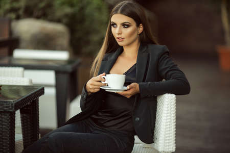 Fashion beautiful business woman with cup of coffee outdoorsの写真素材