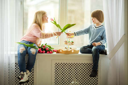 Pretty kids, happy little boy giving a cute girl tulip pink flower. Easter conceptの写真素材