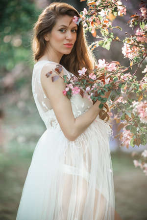 Pregnant pretty woman is posing in pink apple gardenの写真素材