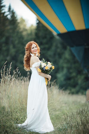 Happy lovely bride is posing infront of airballoon basket outdoorsの写真素材