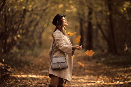 Pretty stylish woman with fashion makeup in autumn park is wearing hat and coat