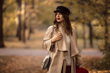 Pretty stylish woman with fashion makeup in autumn park is wearing hat and coatの写真素材