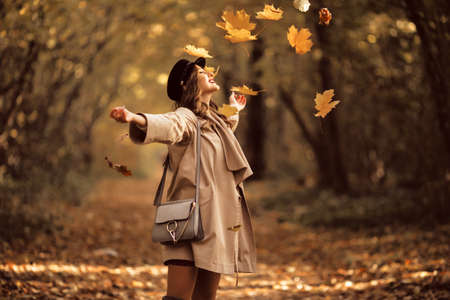 Pretty stylish woman with fashion makeup in autumn park is wearing hat and coatの写真素材