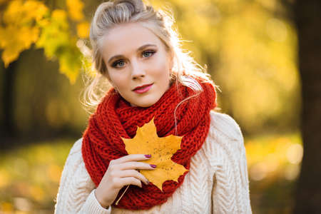 Pretty blonde girl with bouquet of yellow maple leaves