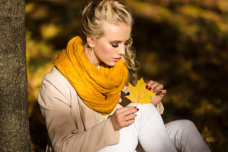 Pretty smiling blonde girl in yellow autumn leavesの写真素材