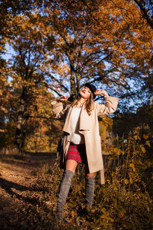 Pretty stylish woman with fashion makeup in autumn park is wearing hat and coatの写真素材