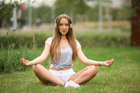 Young sportive girl doing yoga meditation in park in the cityの写真素材
