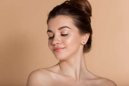Beautiful face portrait of young woman with perfect skin with moisturizing face cream on a cheek. Skin care and health concept.の写真素材
