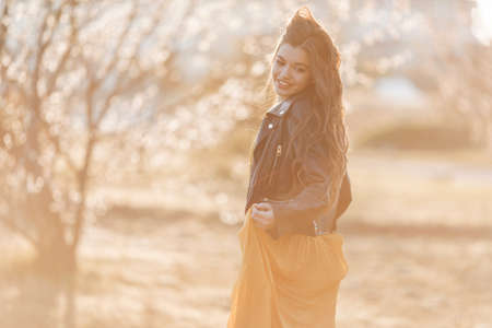Portrait pretty teen girl with long hair posing over sunset lights. Spring time.