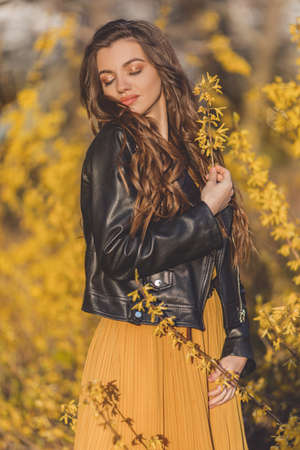 Portrait pretty teen girl with long hair is near aroma bushes with yellow flowers. Spring time.の写真素材