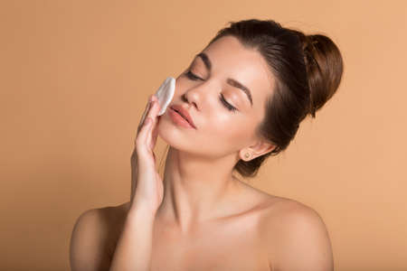 Portrait of young beautiful woman is cleaning her face from makeup with cotton pads. Skin care and beauty concept.の写真素材