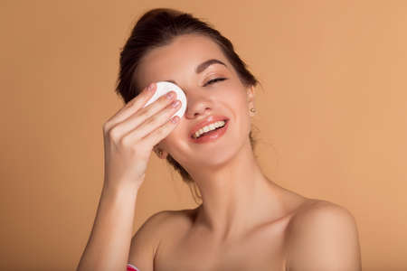 Portrait of young pretty woman with cotton pads cleaning her face. Skin care and beauty concept.の写真素材