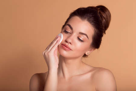 Portrait of young beautiful woman is cleaning her face from makeup with cotton pads. Skin care and beauty concept.の写真素材