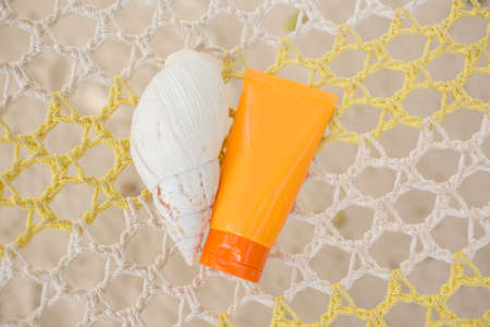 Jar with sunscreen and shell on the hammock. Skin protection concept.
